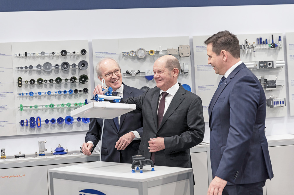 В демонстрационном зале Schmalz федеральный канцлер (в центре) знакомится с вакуумными технологиями от управляющих директоров Schmalz д-ра Курта Шмальца (слева) и Андреаса Бойтеля.