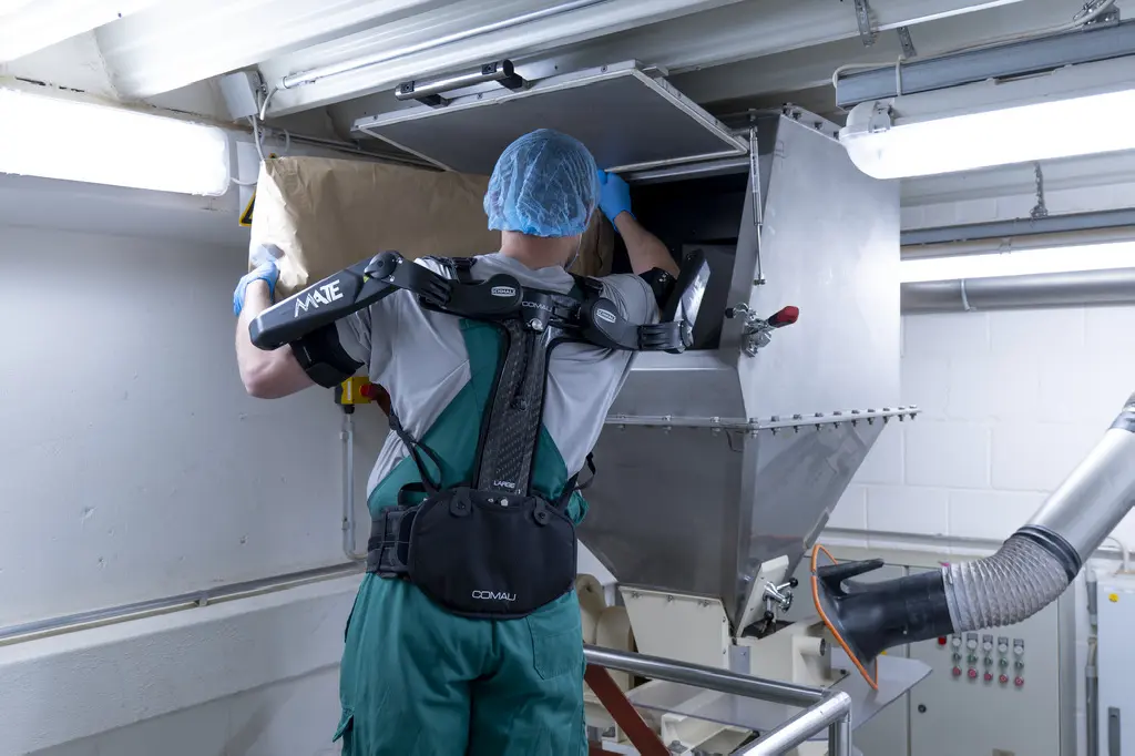 The exoskeleton assists employees with manual lifting tasks, such as loading mixers and mills, which take place at chest height and overhead.