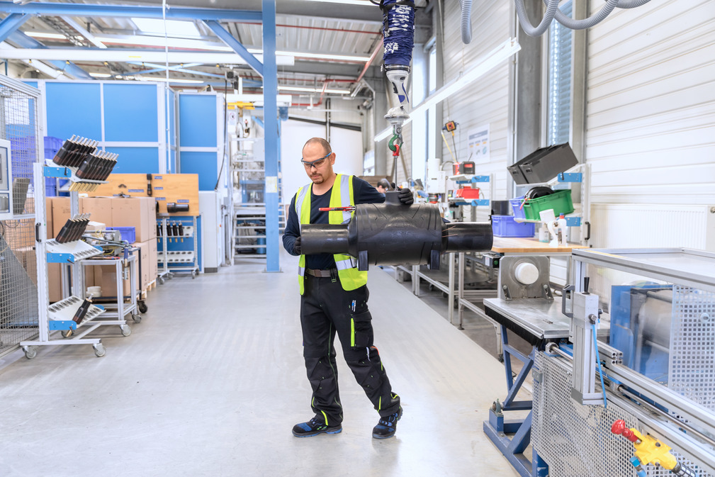 De JumboFlex 50 maakt het gemakkelijk om de tot 40 kilogram zware FRIALOC-sluitfitting van de montagetafel in de lasopstelling te tillen.